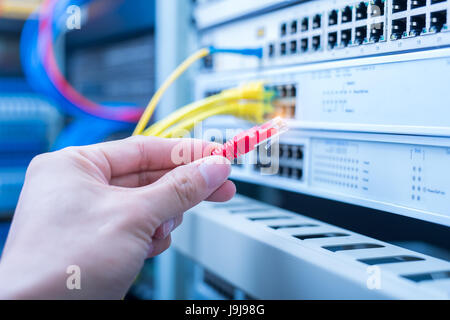 man working in network server room with fiber optic hub for digital communications and internet Stock Photo