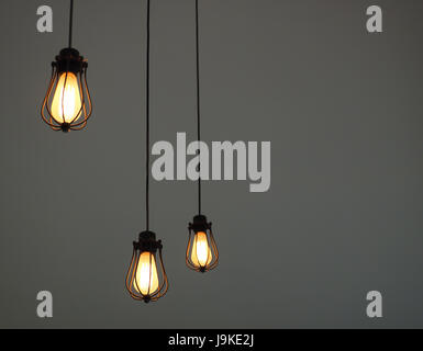Illuminated hanging pendant lights on plain background with free text space Stock Photo