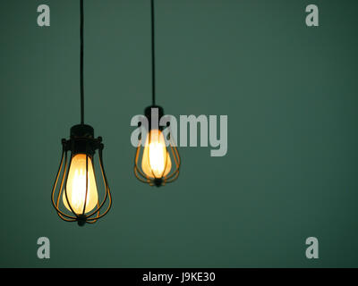 Yellow illuminated hanging light bulbs on plain dark green background with text space