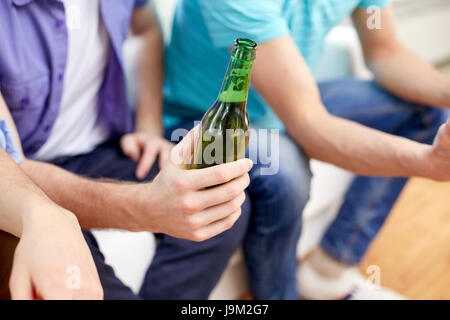 men with beer bottles sitting on sofa at home Stock Photo