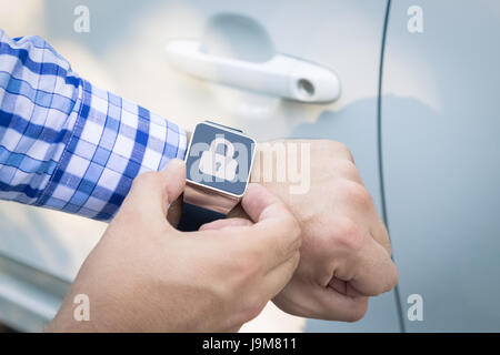 Close up shoot of male hands locking the car doors by using smart watch remote control security app. Stock Photo