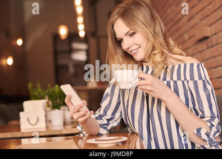 Young woman text messaging while having coffee Stock Photo