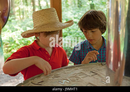 boys writing in sand at barefoot trail, Egestorf, Lower-Saxony, Germany Stock Photo