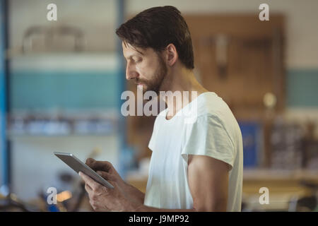 Side view of worker using digital tablet at bicycle workshop Stock Photo