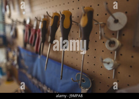 Close up of work tools hanging on rack at bicycle workshop Stock Photo