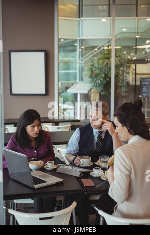 Businesspeople looking at laptop in office cafeteria Stock Photo