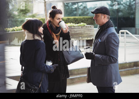 Businesspeople interacting with each other while having coffee in office premises Stock Photo