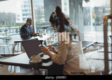 Businesswoman using mobile phone in office cafeteria Stock Photo
