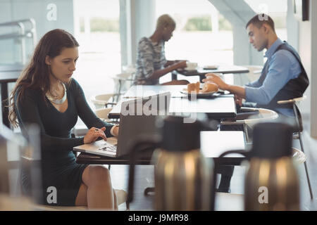 Female executive using laptop in office cafeteria Stock Photo