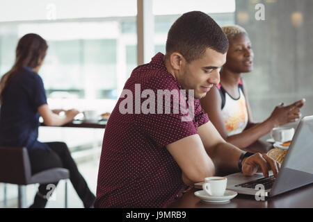 Male executive using laptop in office cafeteria Stock Photo