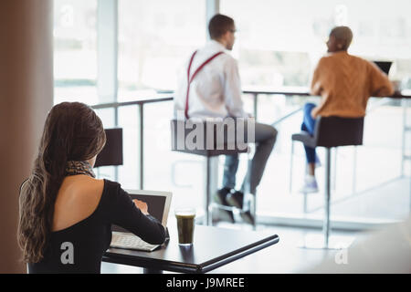 Rear view of female executive using laptop in office cafeteria Stock Photo