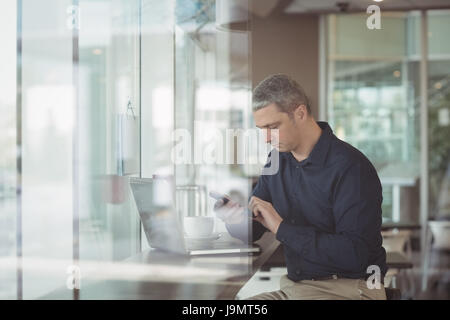 Male executive using mobile phone in office cafeteria Stock Photo
