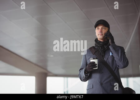 Businessman taking on mobile phone at the entrance of office Stock Photo