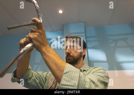 Low angle view of focused worker repairing handlebar at vintage bicycle workshop Stock Photo