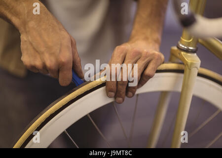 Mid section of employee repairing vintage bicycle wheel at workshop Stock Photo