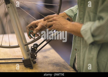 Mid section of worker repairing wheel on table at vintage bicycle workshop Stock Photo