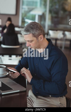 Male executive using mobile phone in office cafeteria Stock Photo