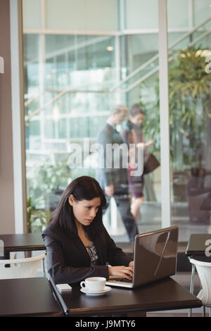 Businesswoman using laptop in office cafeteria Stock Photo
