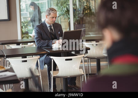 Businessman using laptop in office cafeteria Stock Photo