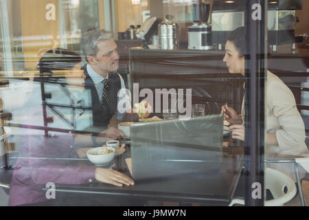 Businesspeople discussing over laptop in office cafeteria Stock Photo