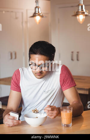 Man using phone while having breakfast at home Stock Photo