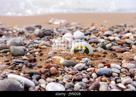 Paphos, Cyprus - November 22, 2016 Pebble with painted sign Batman lying on the sea beach with sand and stones. Stock Photo