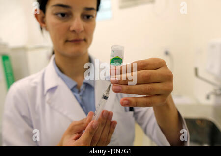 Nurse preparing a dose of vaccine against influenza - flu shot, in a public health office of Sao Paulo city - Brazil - South America