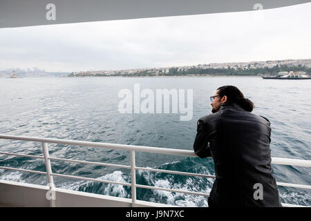 A Turkish man on a ferry across the Bosphorus from Kadıköy to Beyoglu, Istanbul, Turkey.