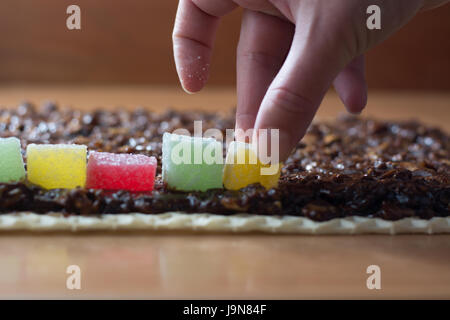 Chocolate topping with wallnuts on cake crust for rolled chocolate cake with jelly candies Stock Photo