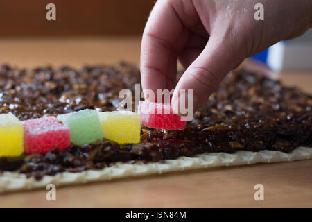 Chocolate topping with wallnuts on cake crust for rolled chocolate cake with jelly candies Stock Photo