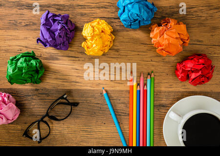 wooden desktop as background with popular glasses and beautiful colors of paper balls and colored pencils placed in copyspace with coffee as advertisi