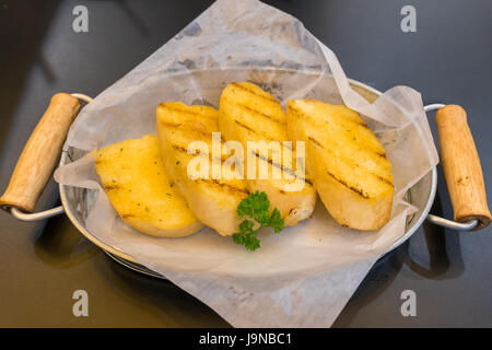 Crispy garlic bread in basket on wooden table Stock Photo