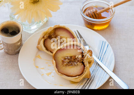 Apple stuffed with nuts and baked in the dough coat served on the white plate with honey, closeup Stock Photo