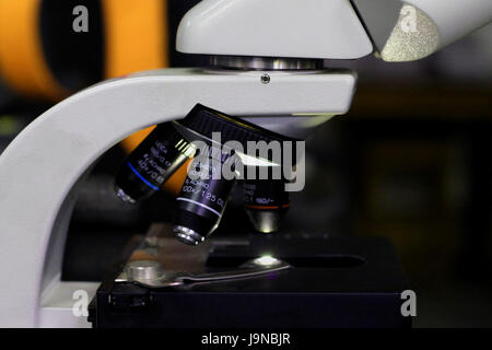 side view of microscope in a research lab showing the objective lenses. Stock Photo