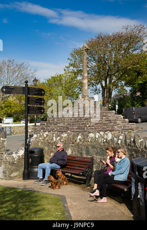 UK, Wales, Pembrokeshire, St Davids, Cross Square, visitors relaxing in sunshine by old stone cross Stock Photo