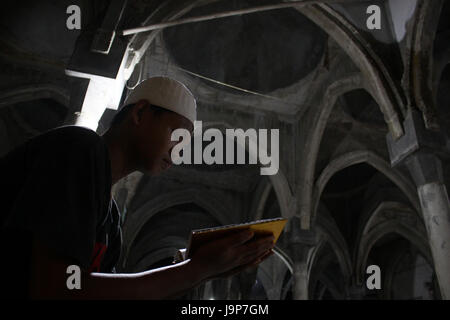 A young man reading Quran after following Taraweh prayer at the Jammi Annawawiyyah mosque during the holy month of Ramadhan, Muslims in Indonesia often their times in the mosque to perform various worship besides salat called I'tikaf, one of them by reading Quran. (Photo by Tubagus Aditya Irawan / Pacific Press) Stock Photo