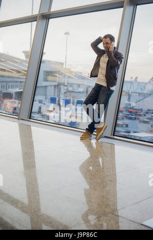 Gonna be home soon. Portrait of a handsome young man laughing speaking on the phone while waiting for his flight at the airport lounge Stock Photo