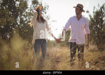Happy young couple holding hands while standing on field at farm Stock Photo