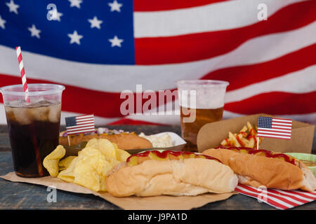 Drinks and snacks arranged on wooden table against American flag Stock Photo