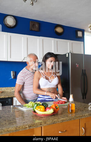 Older man and young woman enjoying cutting vegetables in their kitchen Stock Photo