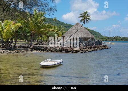 Coastal landscape on the shore of the saltwater lake Fauna Nui with a marae and a traditional hut, Huahine island in French Polynesia, south Pacific Stock Photo