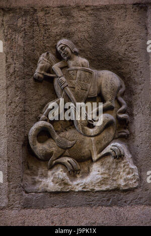 This ancient relief sculpture in Barcelona's old town depicts St. George slaying a dragon.  Barcelona, Spain. Stock Photo