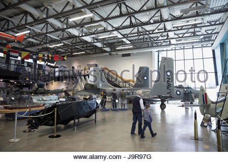 Grandfather and grandson walking, looking at Naval airplanes in war museum hangar