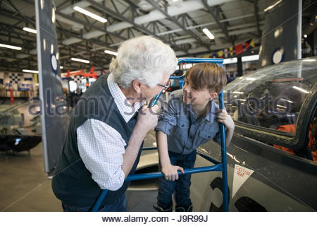 Grandfather and grandson looking at airplane in war museum hangar
