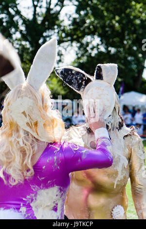 Two men dressed as bunny girls, one pushing custard pie on a paper plate into the face of the other man. Part of the international custard pie championships at Coxheath near Maidestone. Stock Photo