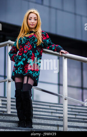Looking up the steps at Alex as she poses in front of the modern Mann Island complex on the Liverpool waterfront. Stock Photo