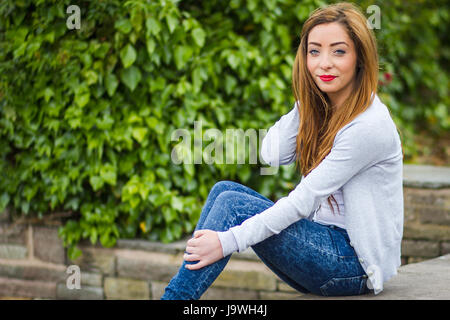 My friend Alex poses at the top of a set of steps in Marine Gardens near Liverpool whilst pushing hair hair back. Stock Photo