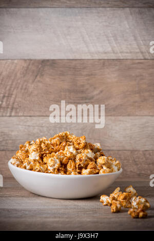 Caramel opcorn in bowl on the wooden table. Stock Photo