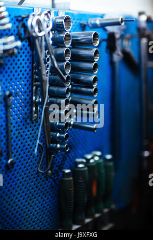Closeup shot of different tools hanging on wall stand in garage Stock Photo