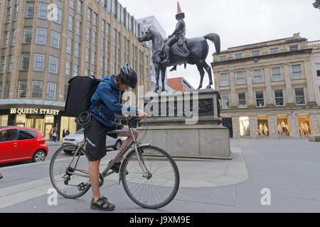 Deliveroo Uber delivery bikers cyclists drivers on the street delivering to Glasgow in view of the cone head Duke of Wellington statue Stock Photo